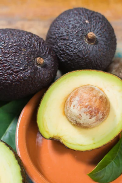 Ripe fresh avocado with leaves on blue wooden table — Stock Photo, Image