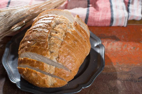 Pan de trigo recién horneado en rodajas y espigas de trigo entero — Foto de Stock