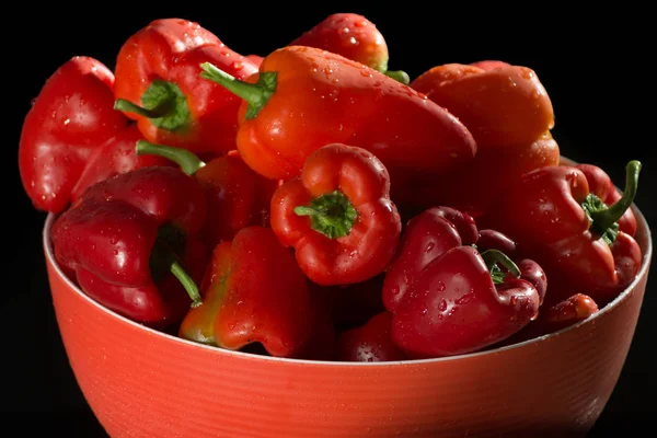 Rote Schüssel mit frisch reifem roten süßen Paprika auf schwarzem Hintergrund — Stockfoto