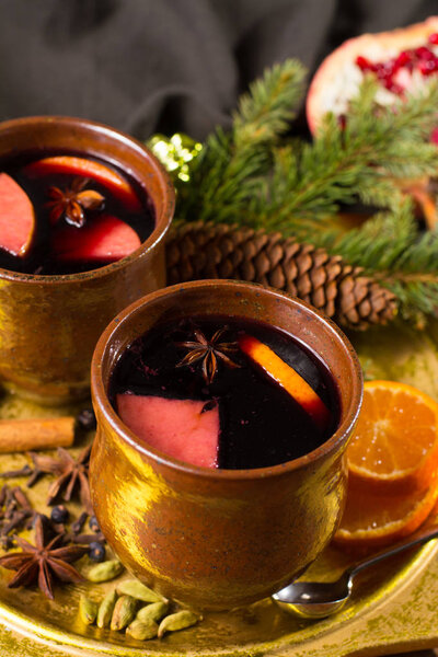 Warm mulled wine for Christmas days, prepared with apple, orange and spices on wooden table with Christmas decoration