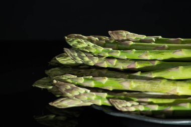 Siyah arka plan üzerine taze çiğ yeşil kuşkonmaz