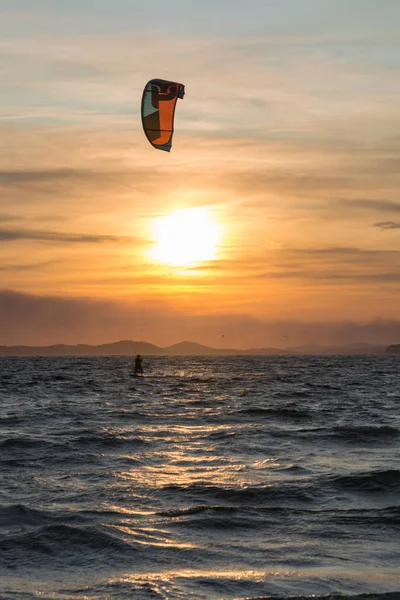 Puesta de sol sobre el mar o el océano y estilo libre extremo kitesur deporte — Foto de Stock