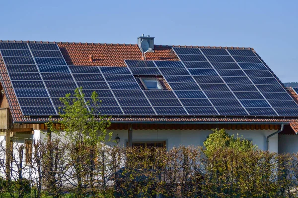 红色屋顶上反射太阳和无云蓝天的太阳能电池板 — 图库照片