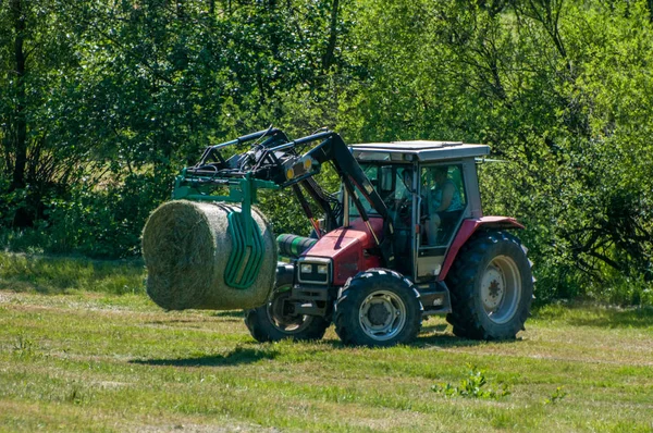 Трактор, що збирає стовбур сіна в полі — стокове фото