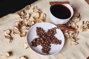 Kahverengi kahve taneleri bir fincan kahve fincanının yanındaki yıldız şeklinde bir fincan üzerinde.