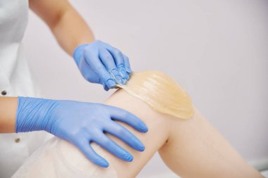 İşlem sallanıyor. Mavi tıp eldivenli bir usta, şeker macununu elle yapılan bir teknikle temizler.