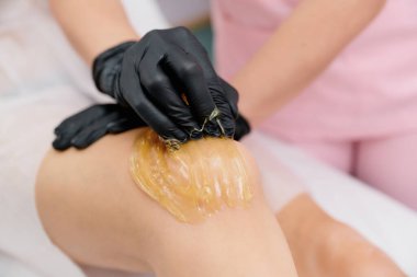 İşlem sallanıyor. Siyah tıp eldivenlerinde uzman, kendi elleriyle şeker yapıştırıcısı sürüyor.