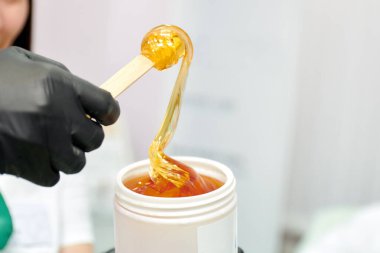 Tahta bir spatula üzerinde beyaz bir kavanozdan şekerleme yapmak için şeker yapıştırıcısı