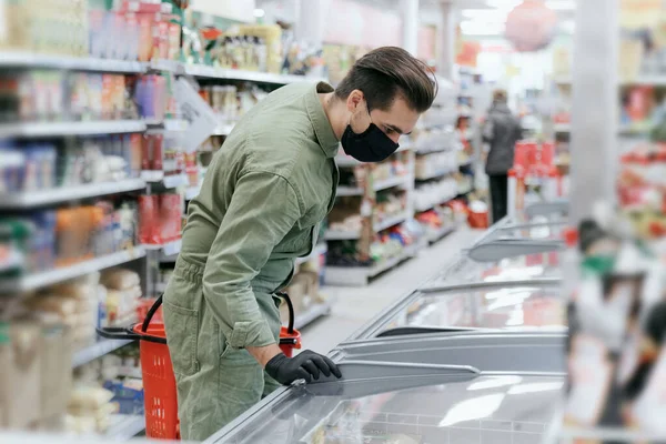 A man in a protective mask selects products in a supermarket