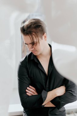 Genç yakışıklı bir adamın portresi. Adam kollarını kavuşturdu.