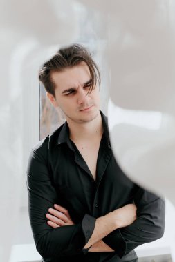 Genç yakışıklı bir adamın portresi. Adam kollarını kavuşturdu.