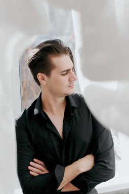 Genç yakışıklı bir adamın portresi. Adam kollarını kavuşturdu.