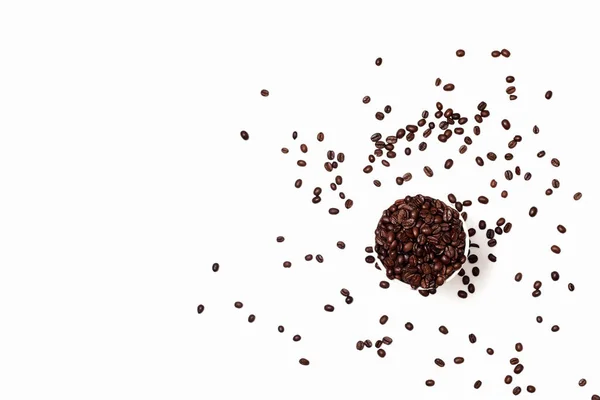 白い背景にコーヒー抽象化されています コーヒー豆とトップビューのガラスガラスの周りに穀物を散在 フレームの右下隅にあるガラスのコーヒー豆は — ストック写真