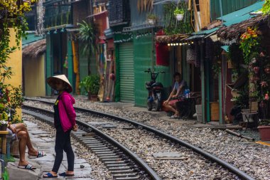 HANOI, VİETNAM, 4 HAZİRAN 2020: Tren sokağında geleneksel şapkalı bir kadın