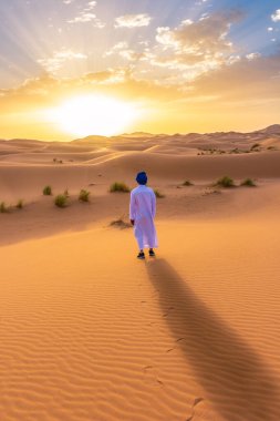 Şafakta Sahra Çölü 'nde geleneksel giysiler giyen berber adam, Fas.