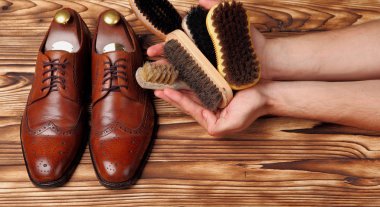 brogues and different brushes for shoes in hands clipart