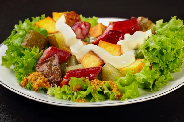 Salad.Chorizo sausage, lettuce, pickled cucumber fried potato with mayonnaise.Dark background — Stock Photo, Image