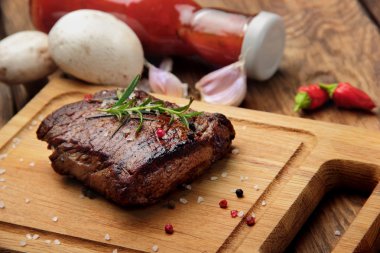 Baharat ve otlar bir rustik ahşap tahta chili biber, sarımsak, ketçap ve mantar çevresinde üzerinde Marine biftek dilimlenmiş dana biftek. Seçici focus.closeup