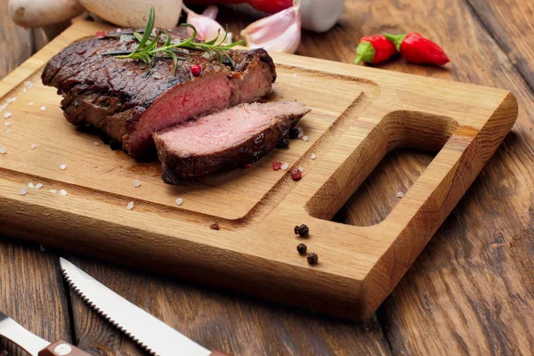 Beef steak sliced beef marinated in spices and herbs on a rustic wooden board chili pepper, garlic, ketchup and mushrooms around.Selective focus — Φωτογραφία Αρχείου