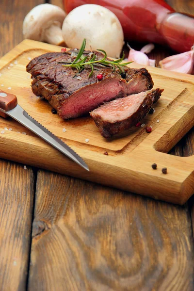 Marha steak, fűszerek és gyógynövények egy rusztikus, fából készült tábla chili paprika, fokhagyma, ketchup és ezen a környéken: gomba pácolt marhahús szeletelt. Szelektív összpontosít — Stock Fotó