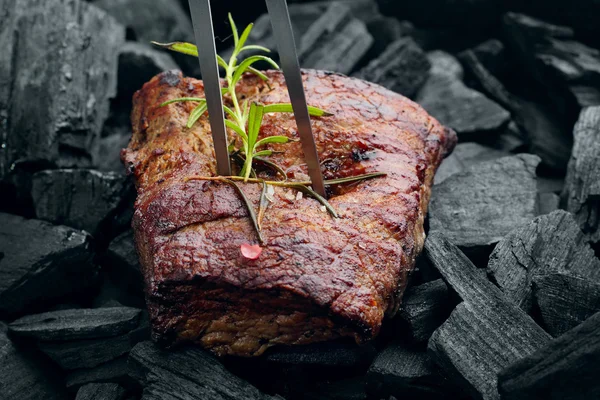 Beef steak on the charcoal with meat fork pierced — Stock Photo, Image