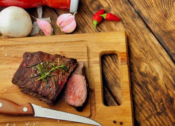 Overhead view of a portion of juicy grilled beef steak with on a textured wooden surface — Stock Photo, Image