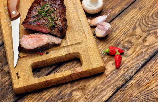 Overhead view of a portion of juicy grilled beef steak with on a textured wooden surface — Stock Photo, Image