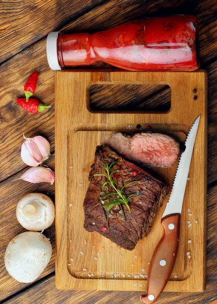 Overhead view of a portion of juicy grilled beef steak with on a textured wooden surface — Stock Photo, Image