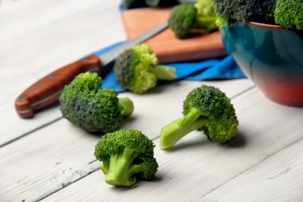 Brokoli tersebar di tablet kayu putih. Focus.knife selektif pada paln kedua yang tidak fokus. — Stok Foto