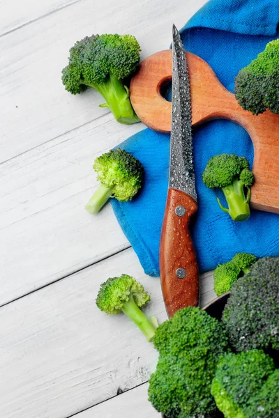 Brocolli di papan potong dengan pisau basah di meja kayu putih. Ruang view.copy — Stok Foto