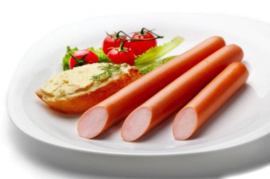 Buutter ve kiraz domates izole beyaz bir arka plan üzerinde beyaz ekmek ile beyaz plaka üzerinde üç sosis. Seçici odak