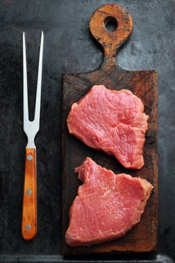 Siyah arka plan çiğ taze mermer et Steak fileto mignon ve rustik kesme tahtası maydanoz ve kırmızı biber ile et çatalı