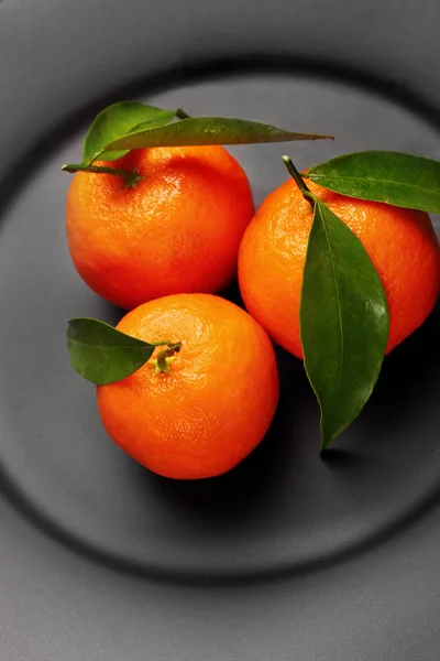 Tangerinas laranja maduras com folhas verdes em placa preta e mate. Conceito de nutrição saudável, dieta, desintoxicação. Foco seletivo.Fechar — Fotografia de Stock