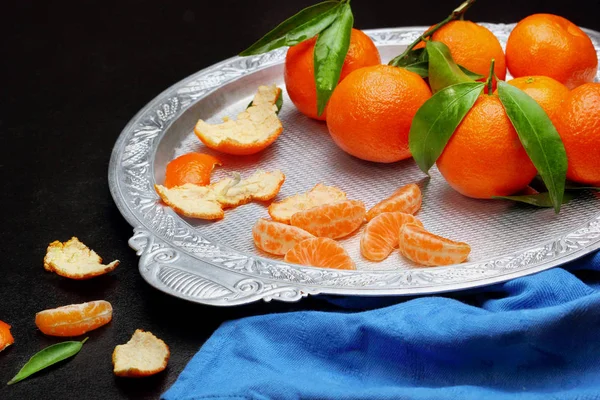 Fresh tangerine clementine with leaves in silver tray on dark stone background, top view.copy space .Selective focus — Stock Photo, Image