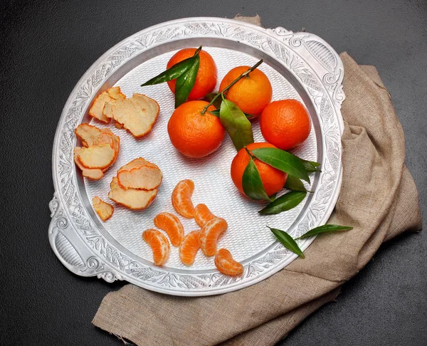 Clementina de mandarina fresca con hojas en bandeja de plata sobre fondo de piedra oscura, vista superior —  Fotos de Stock