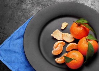 Siyah, matt plaka, üstten görünüm üzerinde yeşil yaprakları ile olgun portakal mandalina. Sağlıklı beslenme, diyet, detoks kavramı. Seçici odak kopya alanı