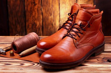 Deri çizmeler ve bootmaker araçları tığ, çivi, skien iplik. Ahşap arka plan. Konsept araçları bootmaker