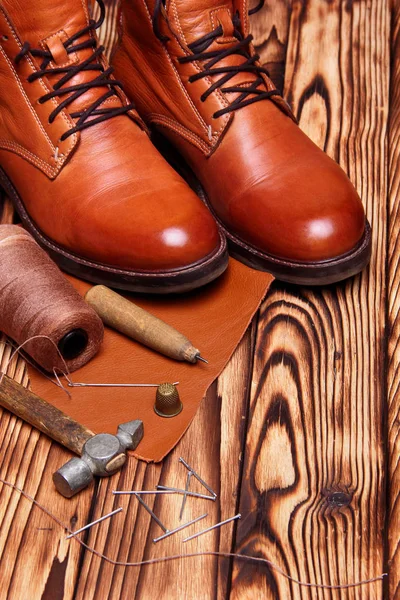 Leather boots and bootmaker tools awl, nails, skien of thread .Wooden background.Concept tools bootmaker.top view. copy space — Stock Photo, Image