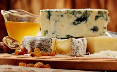 Various types of cheese blue cheese, parmesan, bree with honey, raisins, walnut.Selective focus on bree clipart