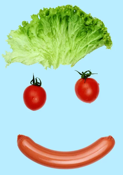 Gelukkig lachend gezicht uit voedsel-worst mond, ogen hair - salade, tomaten. Concept grappige voedsel. Voedsel-art. Voedsel emotie... Blauwe achtergrond — Stockfoto
