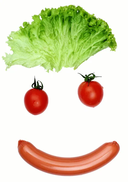 Joyeux sourire visage de la nourriture- bouche de saucisse, cheveux - salade, yeux tomates.Concept drôle aliment.Art alimentaire.Émotion alimentaire.fond blanc — Photo