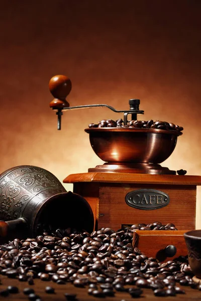 Stilleven met koffiebonen en oude koffiemolen en turk op de houten achtergrond. Stockafbeelding
