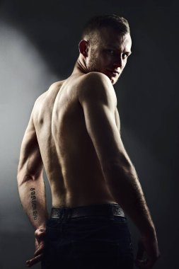Ve arkasında mükemmel muscule gövdeli genç adam ayakta bize geri ve agresif bkz: kot pantolon giymiş..