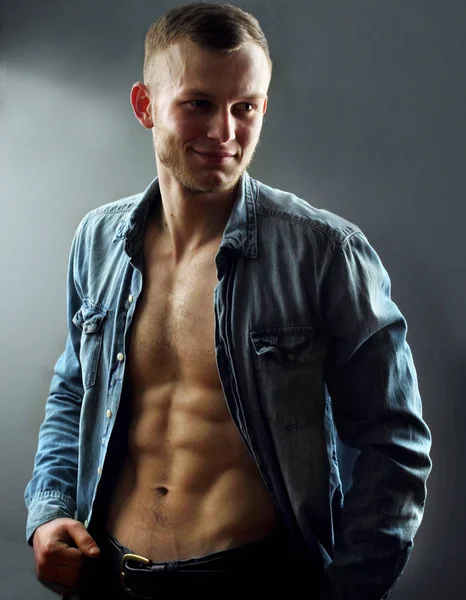 Handsome young man with perfect muscule body dressed in denim shirt and jeans posing.Posing — Stock Photo, Image