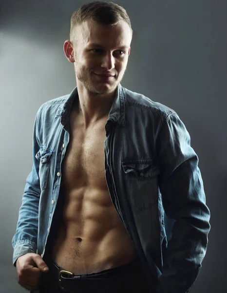 Handsome young man with perfect muscule body dressed in denim shirt and jeans posing.Posing — Stock Photo, Image