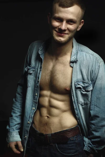 Handsome young man with perfect muscule body dressed in denim shirt and jeans posing.Posing — Stock Photo, Image