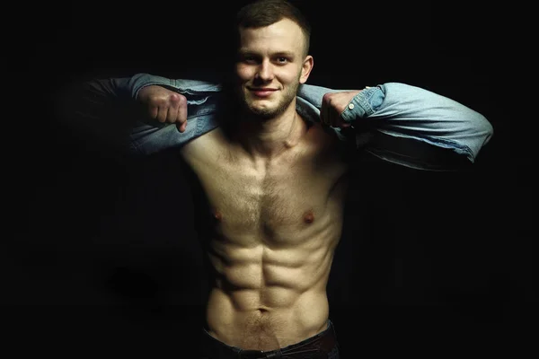 Handsome young man with perfect muscule body dressed in denim shirt and jeans posing.Posing — Stock Photo, Image