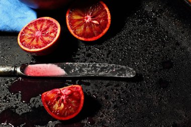Dilimlenmiş Sicilya kan portakal meyve ve karanlık metal arka plan üzerinde parçalanmış qurater. Vintage bıçakla. Üstten Görünüm