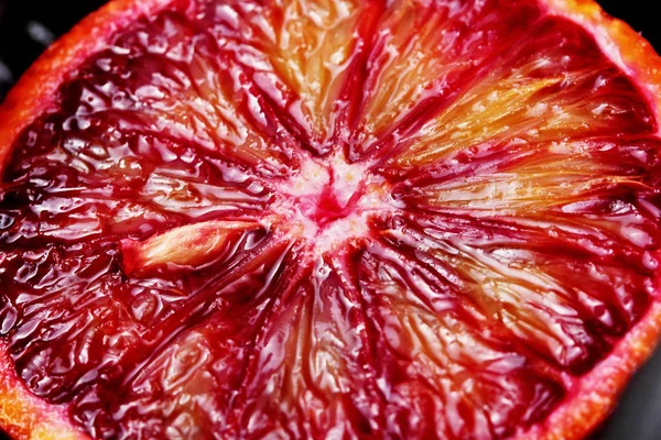 Macro shot de uma secção transversal de uma laranja de sangue mostrando a cor suculenta e vibrante do interior — Fotografia de Stock