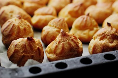 Bir sürü profiteroles(éclair) tepsi choux pasta üzerinde Fransız tatlı. Seçici odak